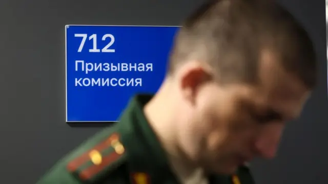 Мужчина в форме на фоне таблички с надписью Призывная комиссия.