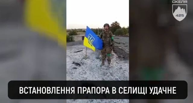 Украинский военный с флагом на крыше здания