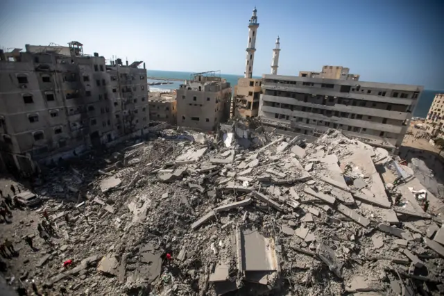 فلسطينيون يتفقدون أنقاض برج الغفاري السكني بعد قصفه بغارة جوية إسرائيلية في مدينة غزة، 15 سبتمبر/أيلول 2025