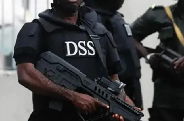 Wani jami'in DSS riƙe da bindiga da wasu jami'an a bayansa