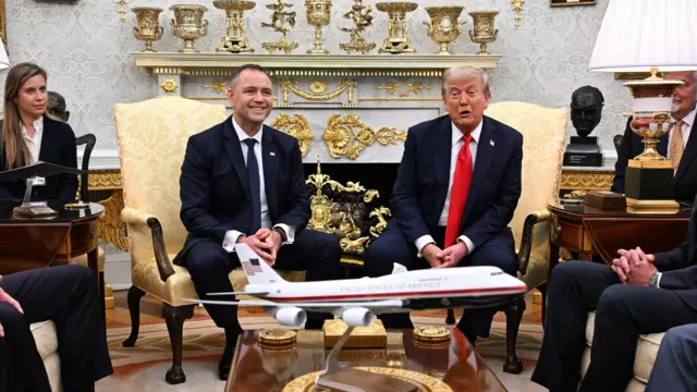 Дональд Трамп и президент Польши Кароль Навроцкий сидят перед камином, отделанным украшениями из желтого металла