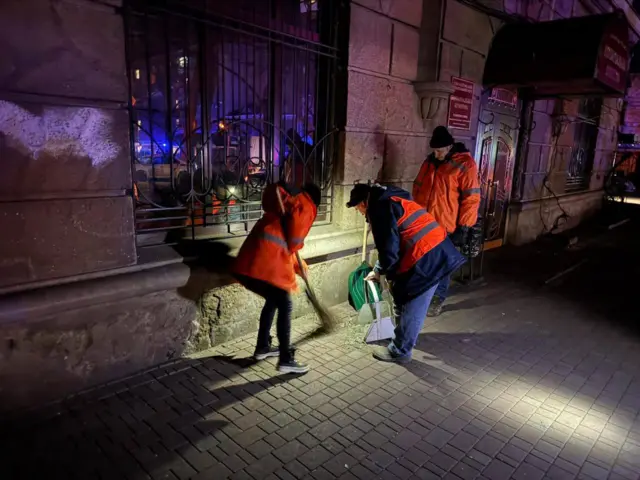 Сотрудники коммунальных служб Одессы сметают разбитые стекла с мостовой
