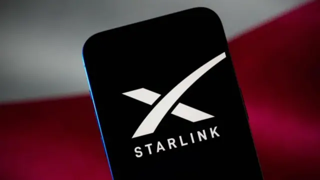 شعارة ستارلينك بلون أبيض باللغة الإنجليزية على شاشة سوداء تظهر على موبايل.