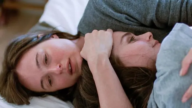 Duas irmãs se abraçando na cama em cena de O Valor Sentimental