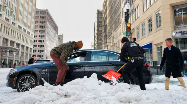 वाशिंगटन डीसी में बर्फ़ में फंसी एक कार को निकालते लोग