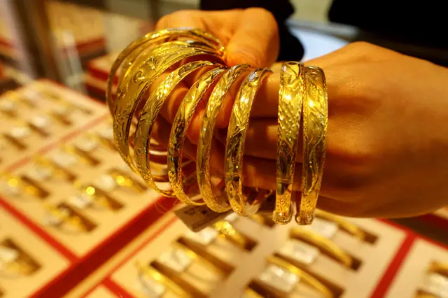 ရွှေလက်ကောက်တွေ ကိုင်ထားတဲ့ လက်ကို အနီးကပ်ရိုက်ထားတဲ့ပုံ