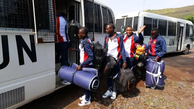 hamwe n'akanyamuneza ku maso, mu myambaro isa, barimo kwinjira mu modoka ya UN