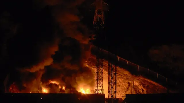 Imagen del incendio en Fuerte Tiuna, el mayor complejo militar de Venezuela, tras una serie de explosiones en Caracas el 3 de enero de 2026. Es de noche y se ven las llamas en la oscuridad.