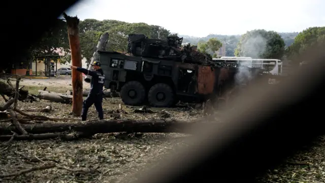 Un bombero gesticula junto a una unidad antiaérea destruida en la base aérea militar de La Carlota, en Caracas.