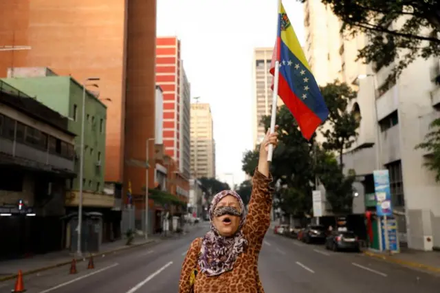 Mulher ergue bandeira da Venezuela em Caracas