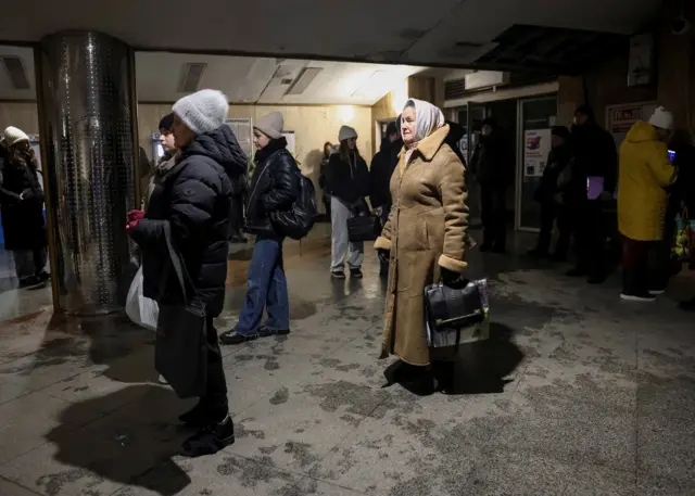 Люди в теплой одежде у входа в метро.