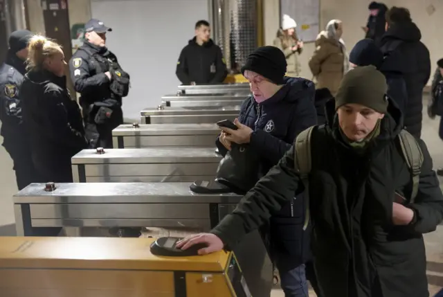 Люди стоят у входа в метро.