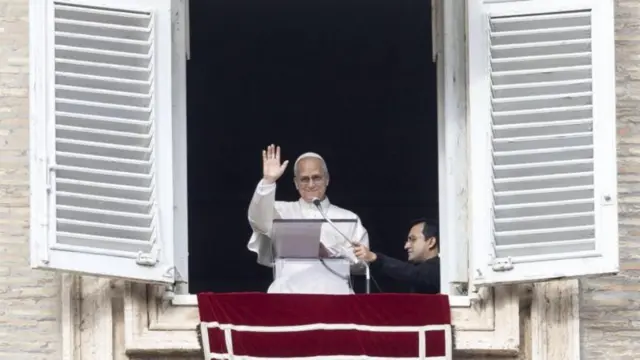Papa Leão 14 acenando com a mão e sorrindo a partir de sacada