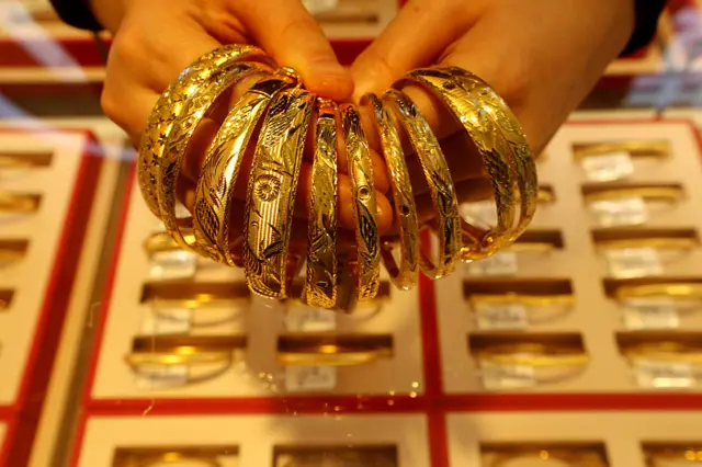 Un empleado de una tienda de oro organiza pulsers de oro para la venta en el mostrador en Lianyungang, provincia de Jiangsu, China, el 24 de diciembre de 2025. (Foto de Costfoto/NurPhoto a través de Getty Images)