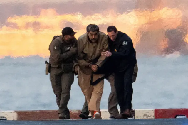 DEA အရာရှိတွေက မာဒူရိုကို ဖက်ဒရယ်အချုပ်ထောင်ကနေ လက်ထိပ်ခတ်ပြီး တရားခွင်ကို ရဟတ်ယာဉ်နဲ့ခေါ်လာ