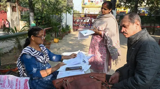 उत्तर प्रदेश के नोएडा में एक स्पेशल बीएलओ कैंप में वोटर लिस्ट नाम की चेकिंग का काम