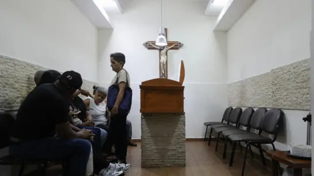 Un grupo de cinco personas junto a un ataúd.