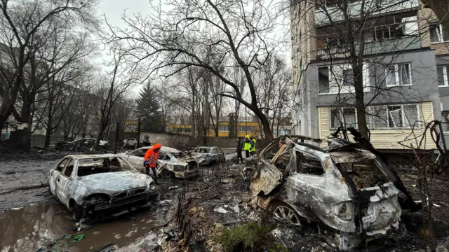 Люди в светоотражающих жилетах осматривают поврежденные автомобили