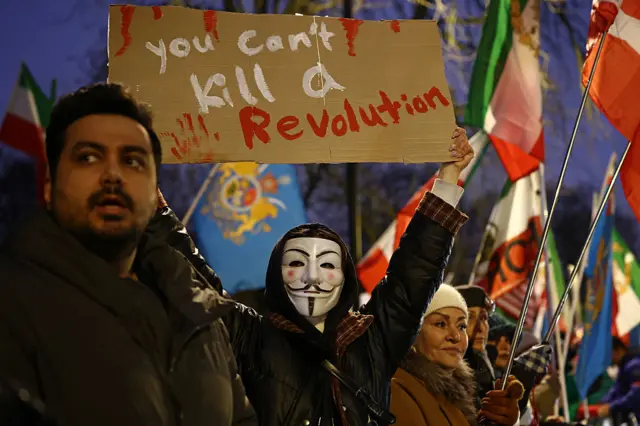 رفع متظاهر مناهض للنظام الإيراني لافتة خلال تجمع أمام السفارة الإيرانية، وسط لندن، في 9 يناير/كانون الثاني 2026.