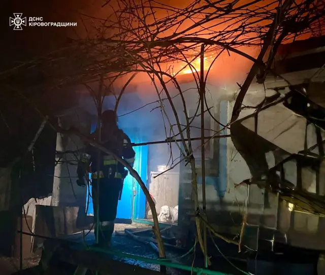 пожарный у дома, поврежденного при воздушной атаке
