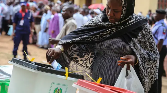 Foto nwaanyị na-etinye akwụkwọ vootu ya n'ime igbe e ji eme ntuliaka