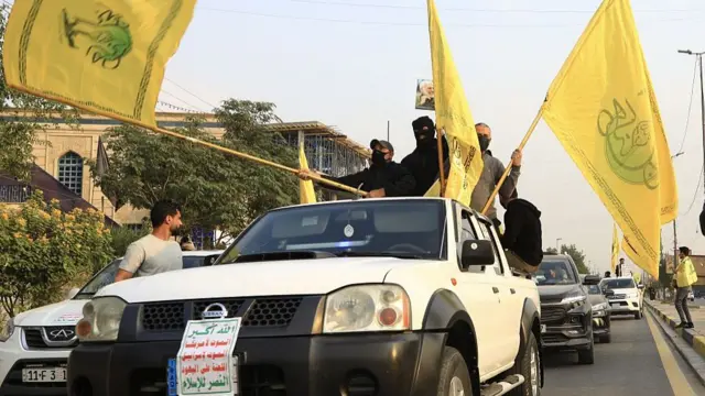اعضای کتائب حزب‌الله عراق با پرچم زرد سوار بر وانت در خیابان‌های بغداد