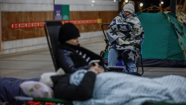 Две пожилые женщины сидят в метро на переносных стульях, укрывшись одеялами