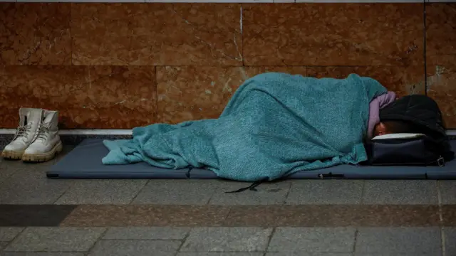 Женщина спит на матрасе, постеленном на полу