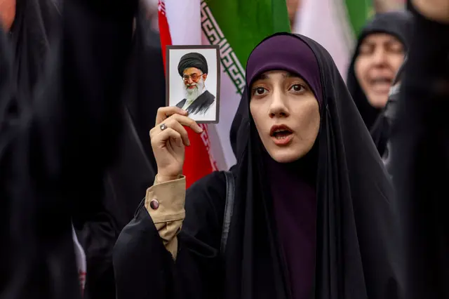 امرأة تحمل صورة آية الله علي خامنئي خلال احتجاجات إيرانية على الهجمات الإسرائيلية والأمريكية على إيران في ٢٨ فبراير/شباط ٢٠٢٦ في طهران، إيران.