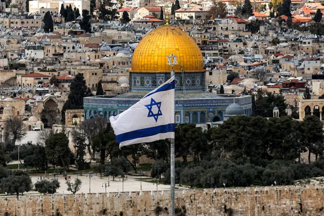 يظهر علم إسرائيلي (في المقدمة) أمام مسجد قبة الصخرة (في الوسط) في باحة المسجد الأقصى بالبلدة القديمة في 9 مارس/آذار 2026