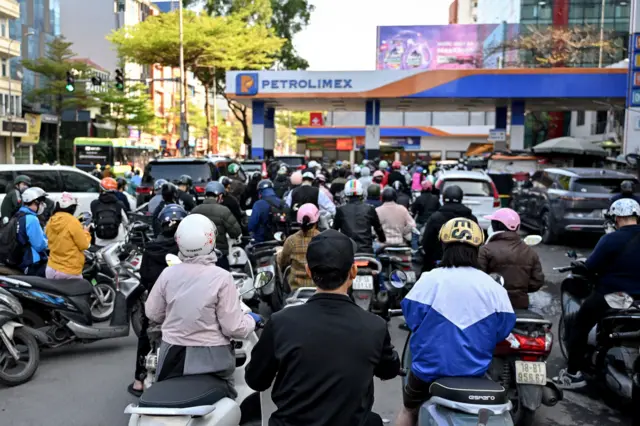 Người dân đi xe gắn máy xếp hàng chờ đổ xăng tại Hà Nội vào ngày 10/3