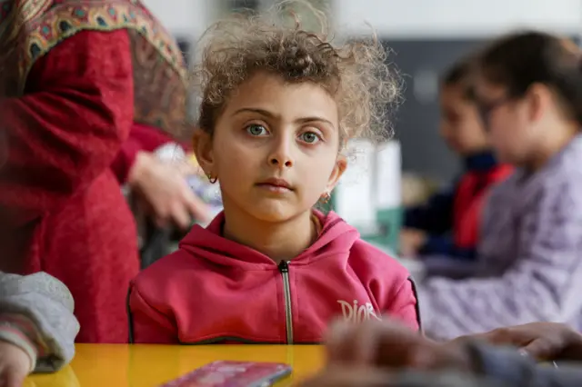 طفلة تراقب أطفالاً آخرين يشاركون في أنشطة بمدرسة تؤوي نازحين مدنيين بعد تصاعد التوتر بين حزب الله وإسرائيل، وسط الصراع الأمريكي الإسرائيلي مع إيران، في بيروت، لبنان، 11 مارس/آذار 2026.