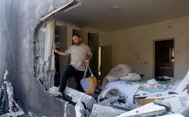 رجل يجمع أغراضه من منزله المدمر في بلدة زرزير بإسرائيل، في أعقاب ضربة صاروخية إيرانية.