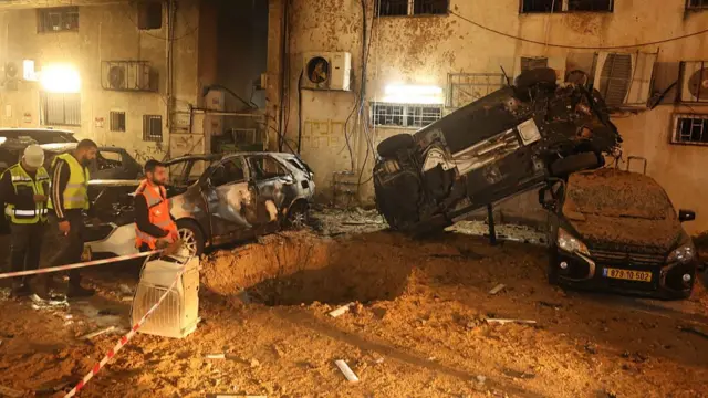 یک ماشین واژگون شده و سوراخی بزرگ در کنار یک ساختمان مسکونی