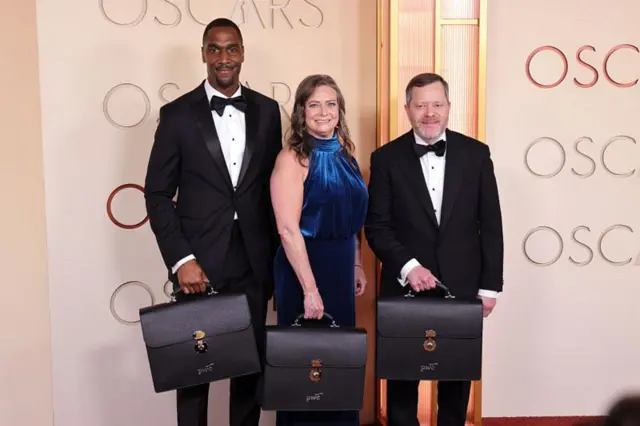 Tres miembros de la firma PricewaterhouseCoopers posan con los maletines de los ganadores de los Oscar.