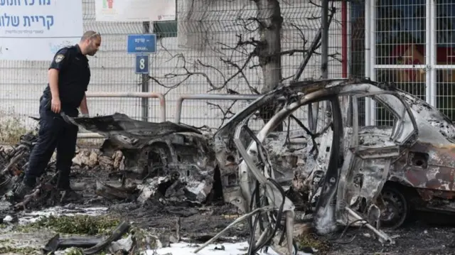 তেল আভিভে পুড়ে যাওয়া গাড়ি পরিদর্শন করছেন একজন ইসরায়েলি পুলিশ