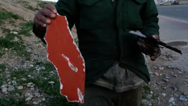 مردی که قطعاتی از چره‌های به‌جامانده از حمله پهپادی ایران به اربیل در روز شنبه را نشان می‌دهد