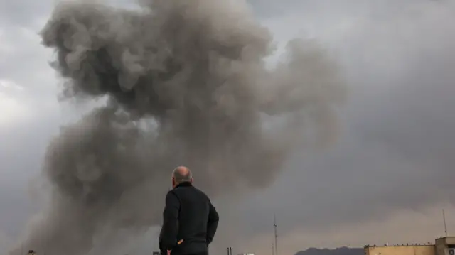 یک فرد به ستون دود ناشی از انفجار نگاه می‌کند