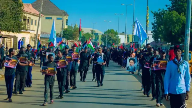 Ndị otu Shia yi uwe ojii jiri ọkọlọtọ mba Ịran n'aka na-eme ngagharịiwe