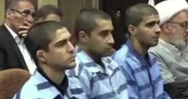 Mavi tutuklu üniforması giyen üç saçları kazınmış genç yan yana oturuyor ve ilerideki hakime bakıyor.