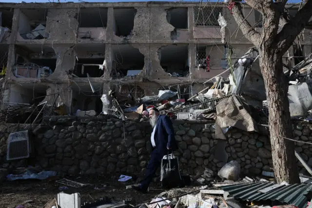 رجل يسير بجوار موقع إصابة مباشرة بصاروخ إيراني في حي سكني بمدينة ديمونا الإسرائيلية، في 22 مارس/آذار 2026