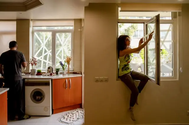 তেহরানের বাসিন্দারা ঘরের জানালায় টেপ লাগাচ্ছেন, যাতে বিস্ফোরণের ধাক্কায় কাঁচ ভেঙে ভেতরে ছিটকে না পড়ে।