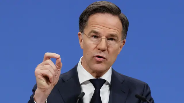 مارک روته، دبیرکل ناتو با کت آبی و کراوات سیاه با پس‌زمینه آبی