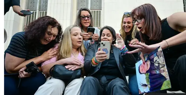 Ifoto igaragaza abahugiye ku mvuga nkoranyambaga bicaye ari itsinda