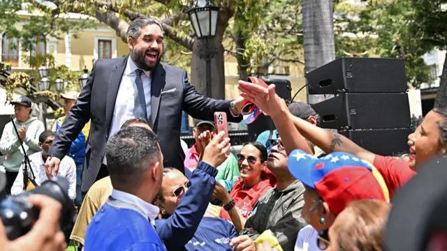 Nicolás Maduro Guerra, vistiendo traje y corbata, saluda a manifestantes que acudieron en apoyo a su padre.