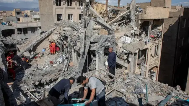 سكان وفرق إنقاذ وسط أنقاض مبنى سكني تعرض لغارة جوية في الساعات الأولى من الصباح.