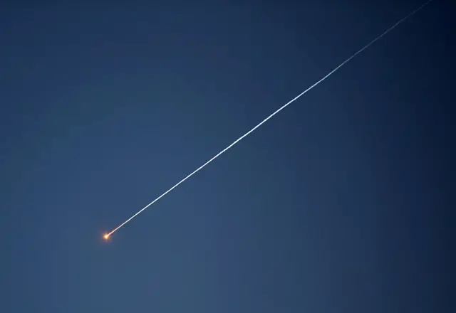 خط من الضوء ناجم عن صاروخ في سماء يميل لونها إلى السواد.