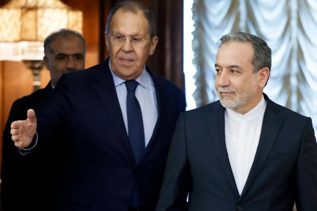 لافروف (يسار) يرتدي بدلة رسمية كحلية اللون مع ربطة عنق، بجانبه عراقجي يرتدي لباسا رسميا كحلي اللون دون ربطة عنق.