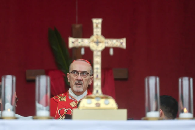 بطريرك القدس للاتين، الكاردينال بييرباتيستا بيتسابالا، مرتديا زيه الكهنوتي وأمامه صليب لونه ذهبي خلال صلاة بمناسبة أحد الشعانين في القدس