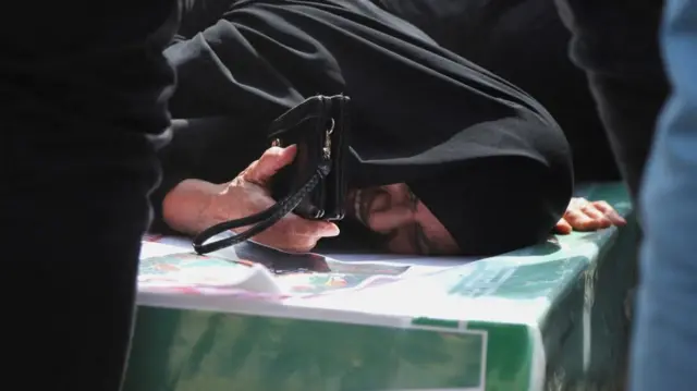 Una mujer llora sobre un ataúd en Minab